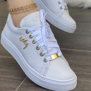 White perforated lace-up sneakers with gold accents and a gold toe detail.