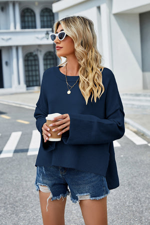 Navy acrylic sweater with flared sleeves and slit hem detail.