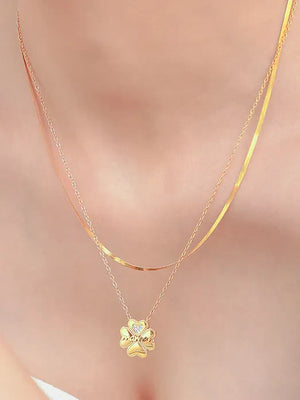 Gold layered necklace with a clover charm featuring a small diamond accent.
