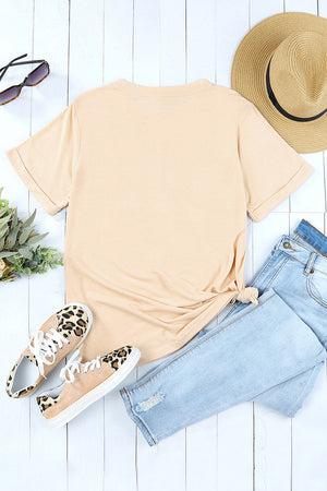 Sand crop top graphic tee with rolled sleeves and a knotted hem, styled with jeans and leopard print sneakers.