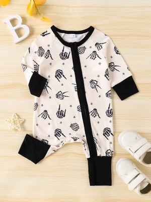 Beige baby one-piece with skeleton hand print, black trim and cuffs.