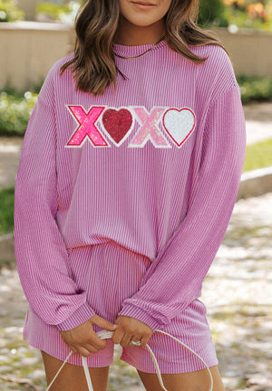 Pink striped loungewear set with sequined XOXO and heart graphic on top.