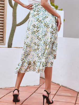 Asymmetric wrap skirt with leaf print and ruffled hem, styled with black heels.
