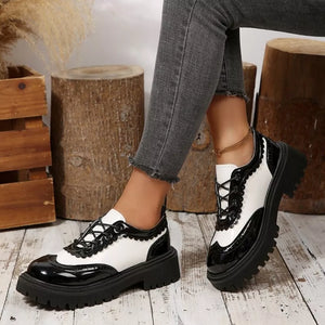 Round toe platform loafers with brogue detailing in black and white patent leather.