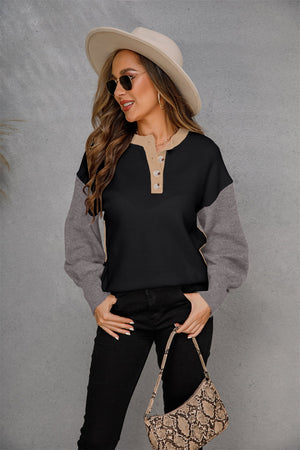 Colorblock henley sweater in black and grey acrylic with button detail and tan collar.