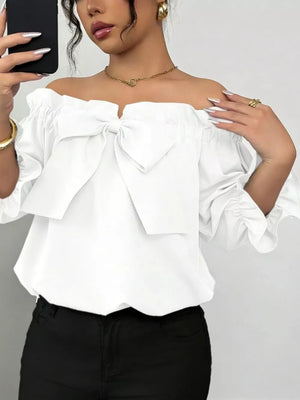 White off-shoulder blouse with ruffled bow detail and puff sleeves.