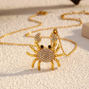 Gold-plated crab pendant necklace with crystal accents and black eyes on a delicate chain.