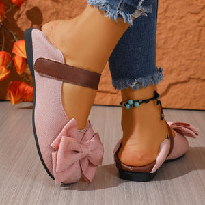 Pink textured round toe flats with bow detail and ankle strap.