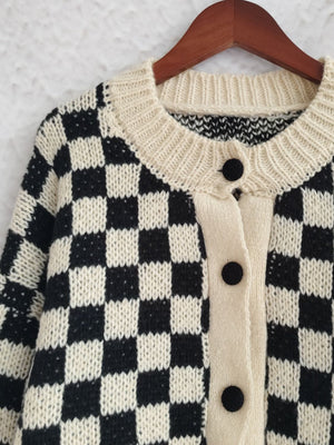 Black and cream checkerboard knit button-up cardigan with cream trim and buttons.