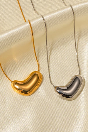 Gold and silver bean-shaped sculptural pendant necklaces on snake chains
