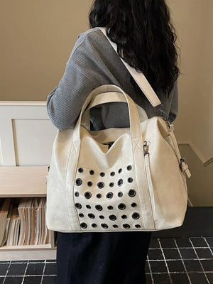 Cream travel organizer bag with eyelet detail and detachable strap.