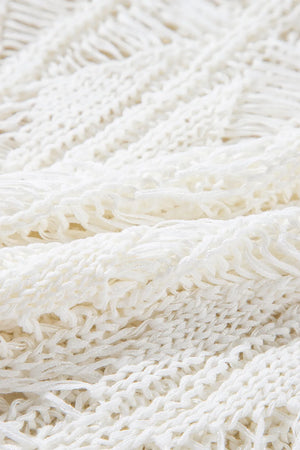 Open-knit crochet sweater in ivory with fringe detail and a cotton blend texture.