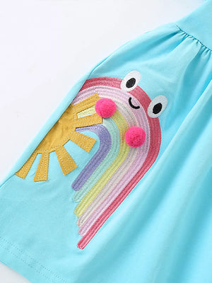 Light blue cotton babydoll dress with rainbow embroidery, sun applique, and pom-poms.
