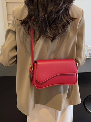 Red faux leather crossbody bag with a curved flap and gold hardware.