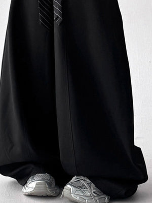 Men's black wide leg sweatpants with drawstring detail and striped tie, styled with silver sneakers.
