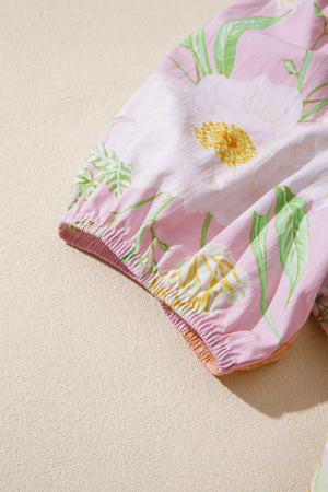 Floral tiered dress with puff sleeves in pink cotton featuring white and yellow flowers and green leaves.