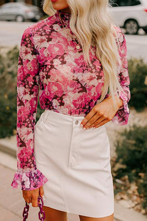 Sheer pink floral print blouse with ruffle cuffs and mock neck.