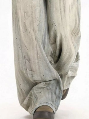 Light vintage wash wide-leg denim trousers with distressed details and paint splatters.