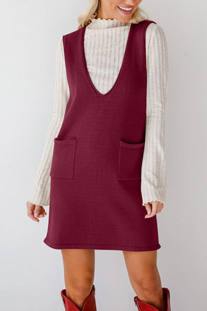 Burgundy knit sweater dress with deep V-neck and two front pockets, styled over a cream ribbed turtleneck.