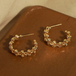 Gold textured orb C-hoop earrings with unique knot-like details.