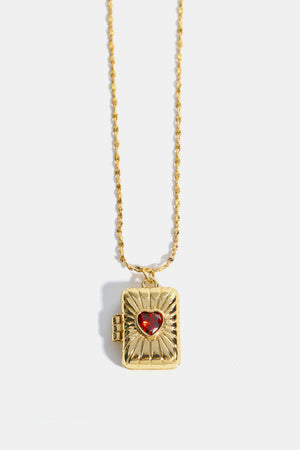 Gold locket pendant necklace with a red heart-shaped gem and sunburst detail.