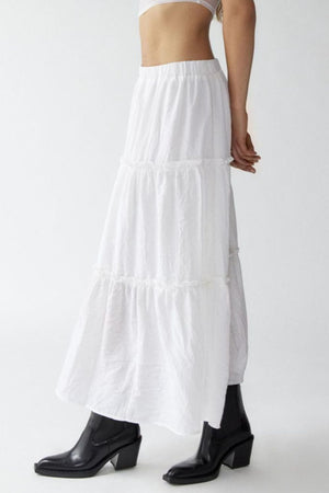 Tiered cotton maxi skirt in white with ruffled seams, styled with black boots.