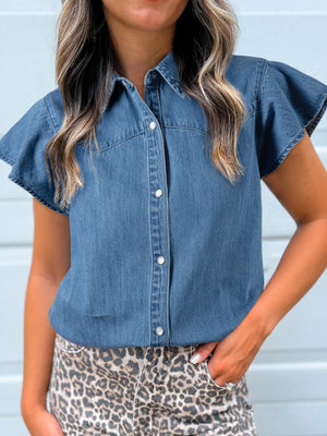 Ruffled denim button-up shirt with short flutter sleeves and pearl buttons.
