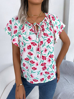 White floral ruffle sleeve tie-neck blouse with red and pink flowers.
