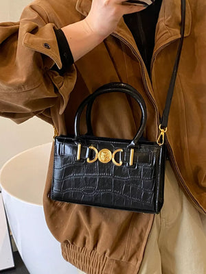 Black crocodile-textured crossbody bag with gold hardware and top handles.