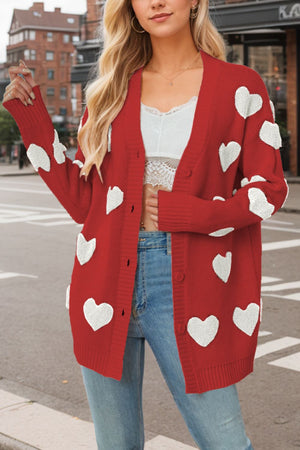 Red knit cardigan with white heart appliqués, button front, and ribbed cuffs.