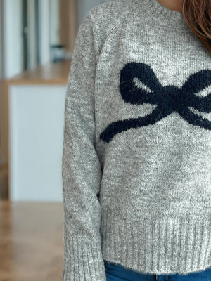 Gray knit sweater with intarsia bow design and crew neck.