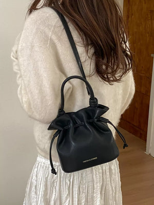 Black pu leather cinch-top crossbody bag with drawstring and knotted handle detail.