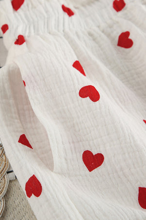 White gauze pajama set with red heart print, showing texture and pocket detail.