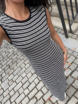 Sleek black and white striped knit maxi dress with a sleeveless, bodycon fit.