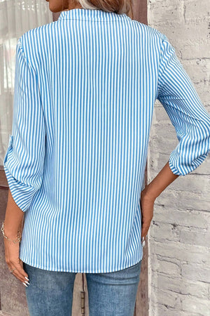 Light blue and white vertical stripe V-neck blouse with rolled sleeves.