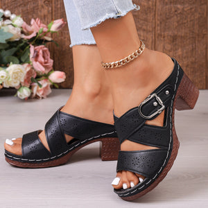 Black laser-cut criss-cross block heel sandals with buckle detail.