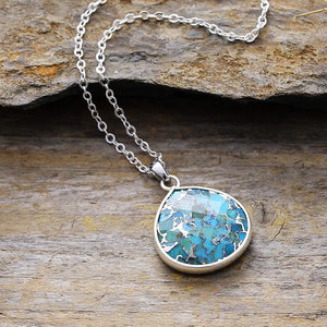 Silver-framed turquoise stone pendant necklace with a delicate chain.