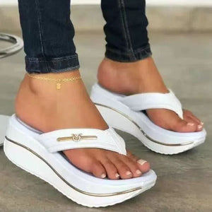 White platform sandals with elegant emblem detail and gold trim.