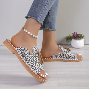 Open-toe slide sandals in white leopard print with tassel detail and decorative stitching.
