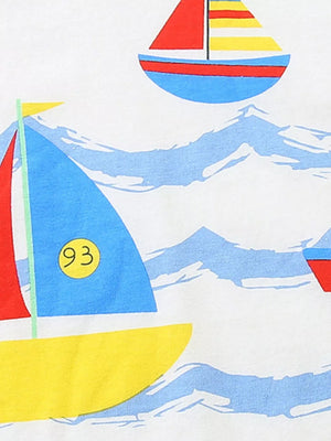 White cotton t-shirt with a nautical sailboat print featuring blue, red, and yellow sailboats on blue waves.