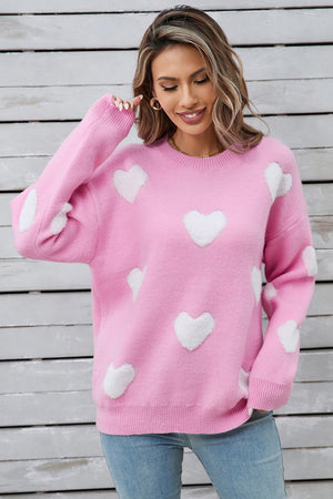 Hot pink crewneck sweater with white heart appliqués and ribbed cuffs.