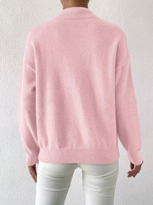 Pink mock neck knit sweater with dropped shoulders and ribbed cuffs and hem.