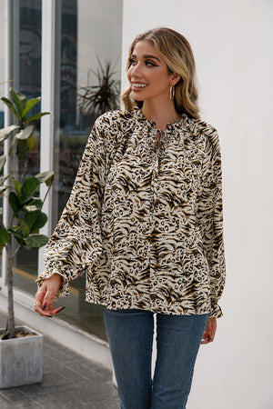 Animal print blouse with ruffle neckline and tie detail, long sleeves.