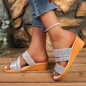 Silver sequined wedge sandals with crisscross straps and a wooden sole.