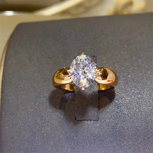 Gold ring with oval moissanite solitaire and sculpted band.