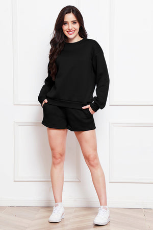 Black crewneck sweatshirt and pocket shorts loungewear set on a woman.