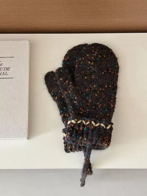 Textured brown knit mittens with zig-zag detail and pom-pom tie.