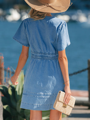 Chic denim dress with elastic waist, short sleeves, and tiered hem detail.