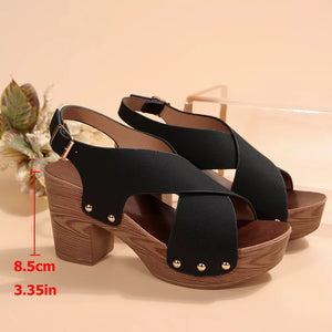 Black crisscross high heel sandals with adjustable strap and stud details on a wooden platform sole.