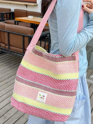 Vibrant striped woven shoulder bag with pink strap, featuring pink, yellow, and white stripes.